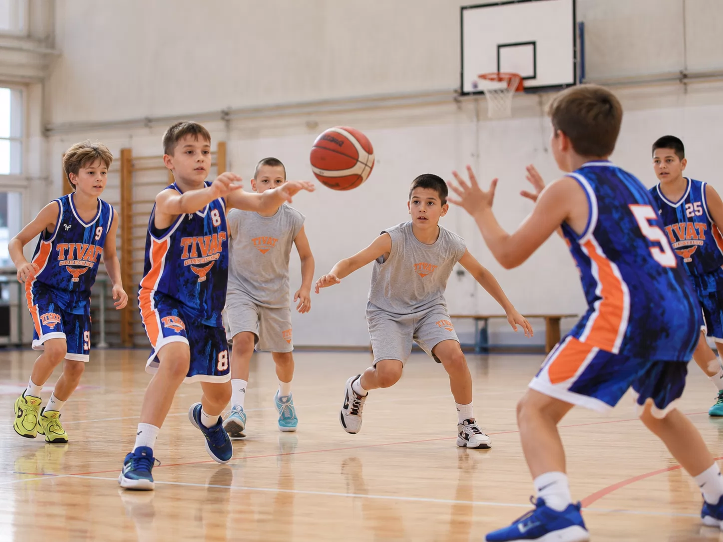 Young players practising a pass in the basketball gym.
