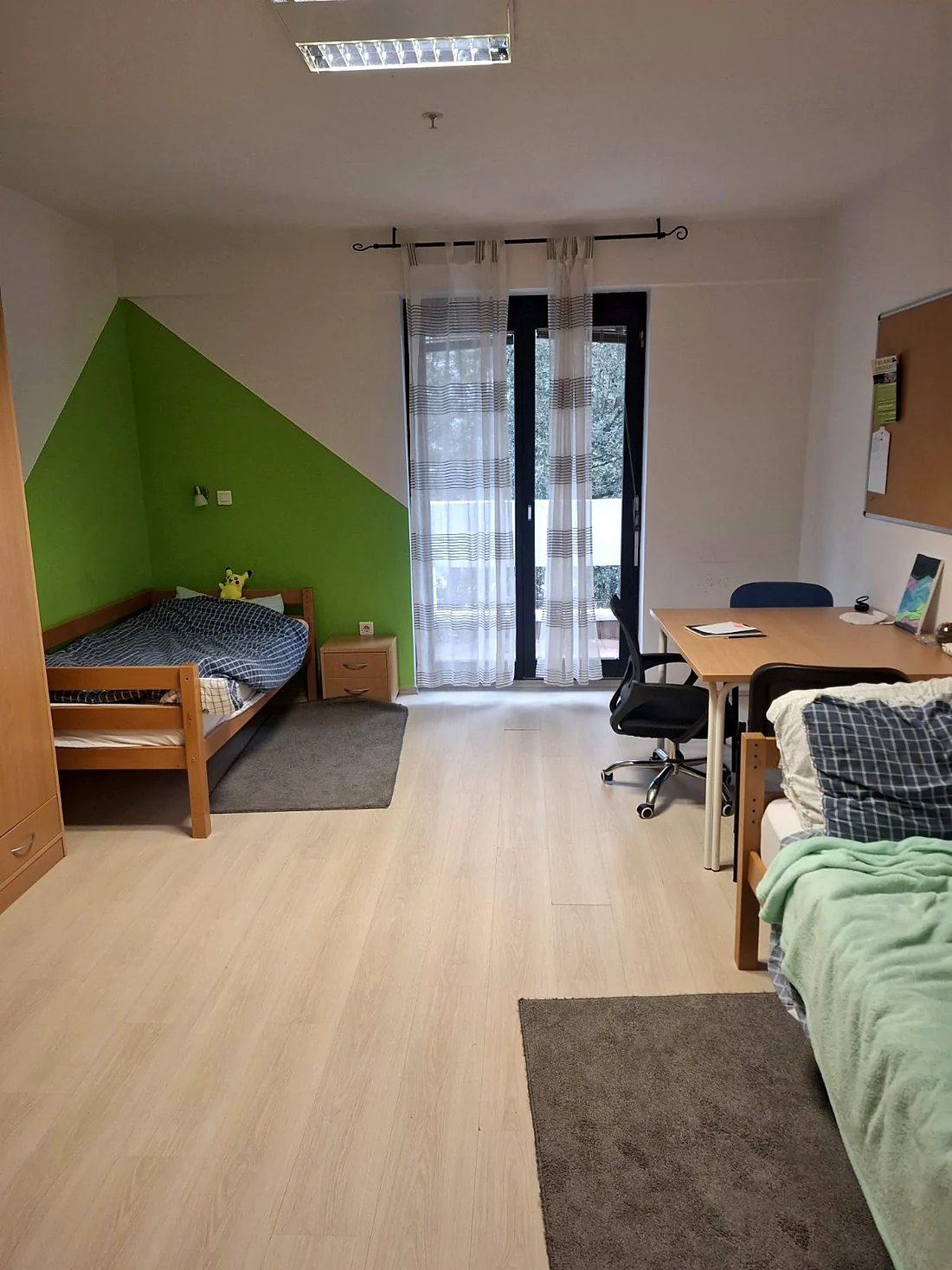 Soba u KSI Montenegro sa dva kreveta, radnim stolom i balkonskim vratima.